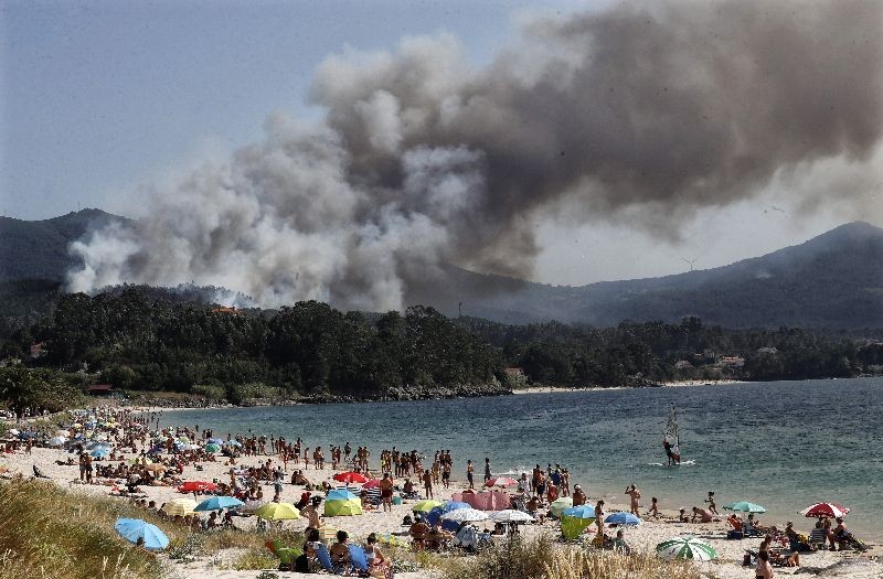 Smoke rises from the forest fire originated next to a touristic beach in Porto de Son, A Coruna, northern Spain. (Photo by Lavandeira Jr./EPA/EFE)